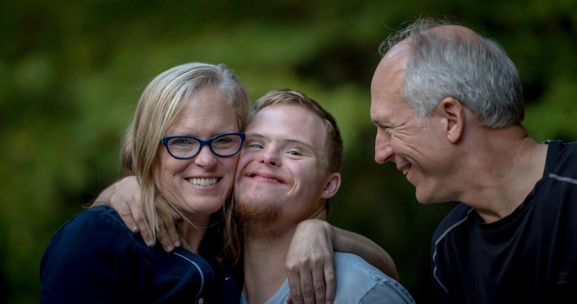 A white family smiling and hugging.