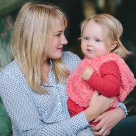 A white woman holding a toddler in a red sweater.