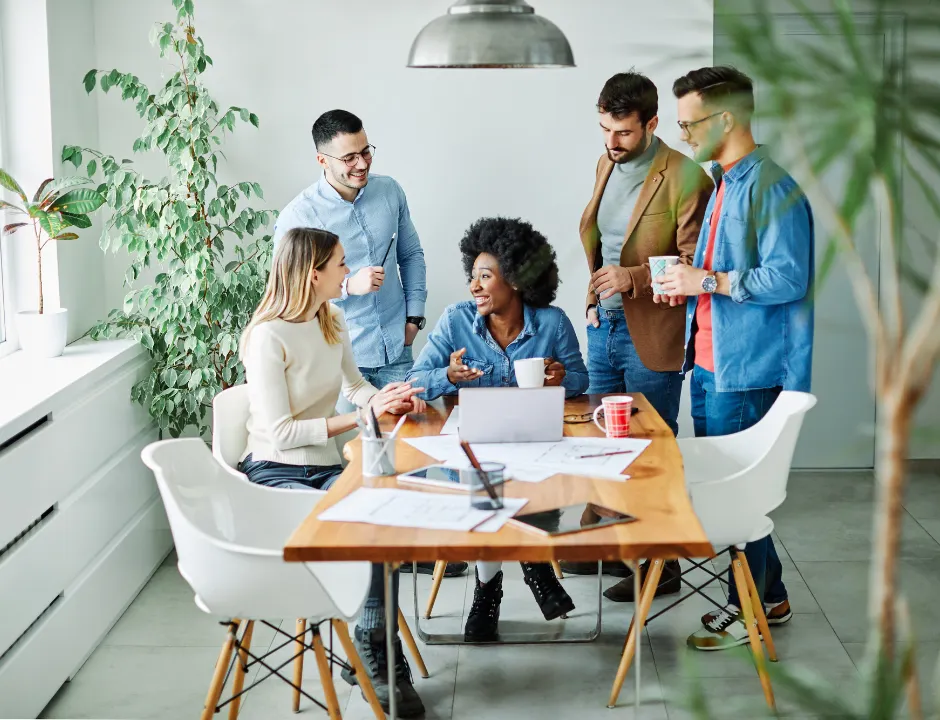 A diverse group of professionals engaged in a meeting around a conference table in a modern office setting.