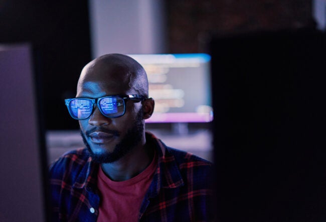 Man with glasses working on a computer to show how AI analytics help revive newly public firms