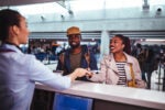 Couple smiling while interacting with an airline customer service agent at the airport