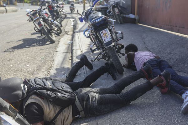 Des passants se mettant à l'abri de l'échange de coups de feu entre les gangs et la police à Port-au-Prince, en Haïti, 11 novembre 2024.