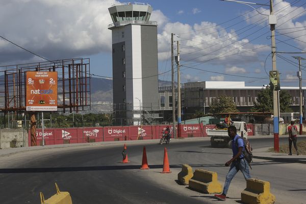 Des piétons passant devant l'aéroport international Toussaint Louverture le jour de sa réouverture à Port-au-Prince, Haïti, le mercredi 11 décembre 2024.