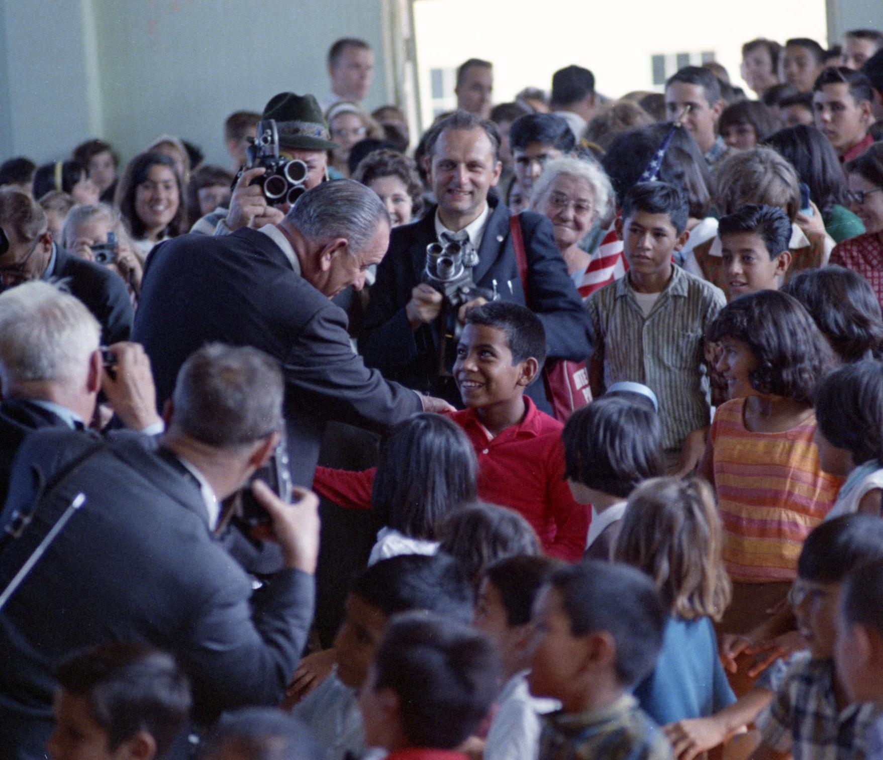 President Johnson speaks with a young boy while visiting the Wellhausen School in Cotulla, Texas.