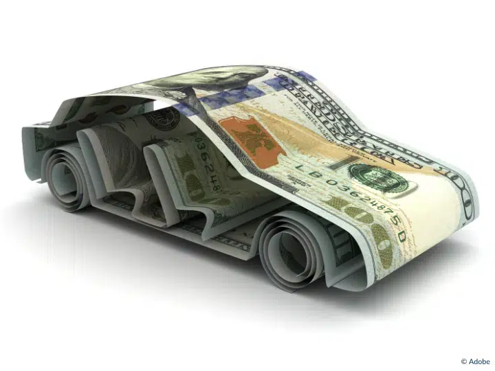 Multiple dollar bills have been origami-folded into the shape of a car.