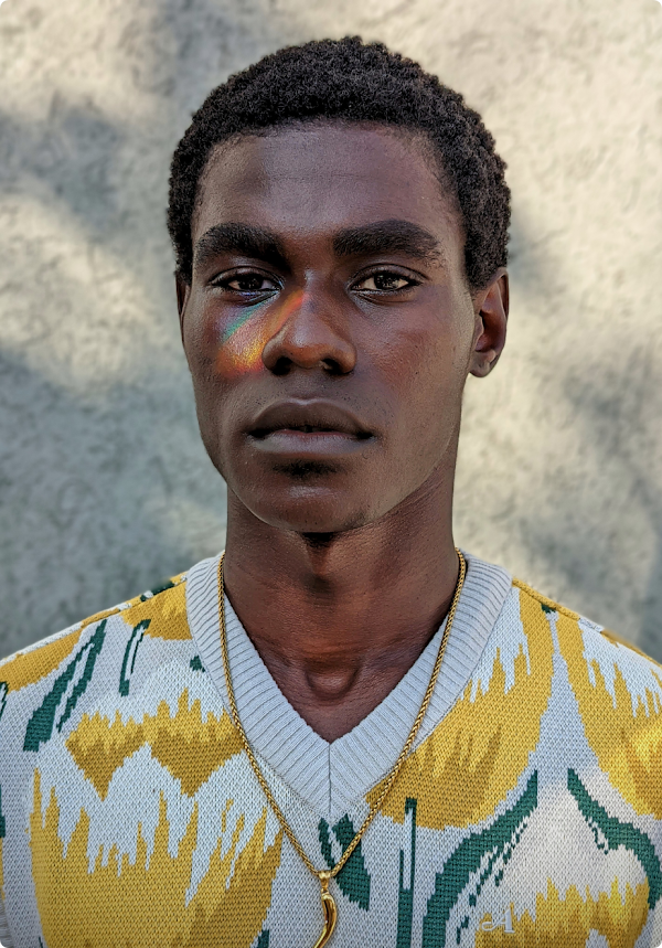 A high quality photo of a Black man looking straight at camera with a rainbow light reflection over his right eye