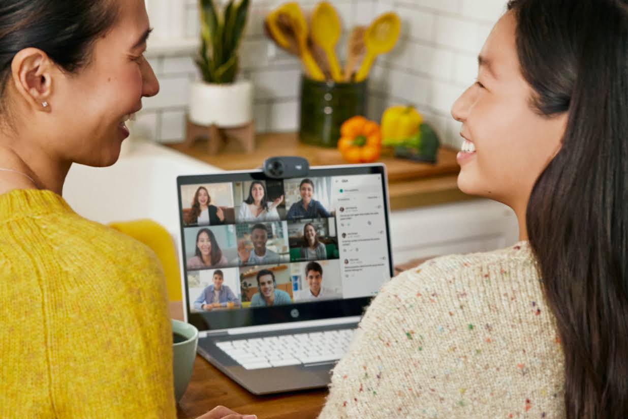 Dos personas sentadas en una cocina se sonríen mientras participan en una llamada de Google Meet.