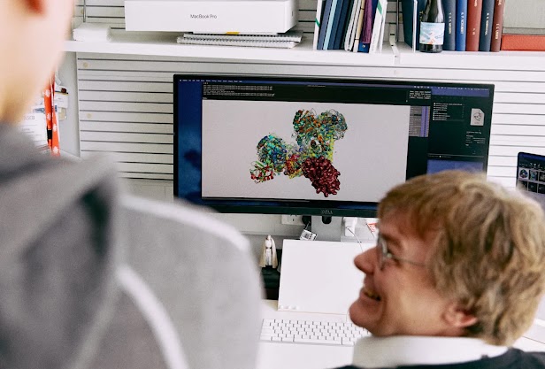 David Komander showing his colleagues work on his computer screen. He looks very pleased with the work.