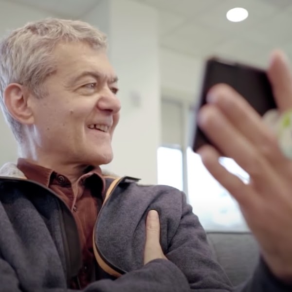 A man speaks into his phone and smiles