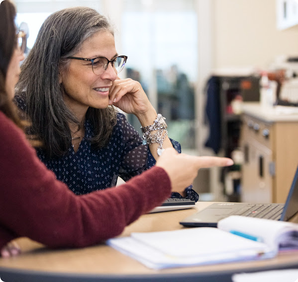 A student points at a computer while a teacher looks where they point.