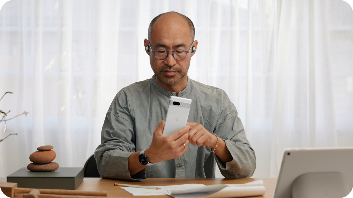 A man using a Google Pixel 7a phone in his office.