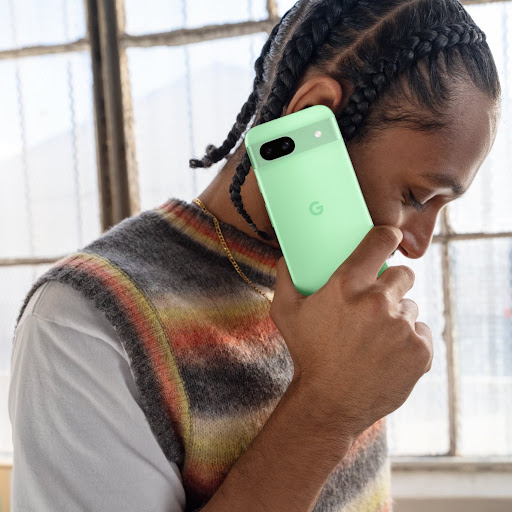 A person takes a call on their Pixel 8a in Aloe color.