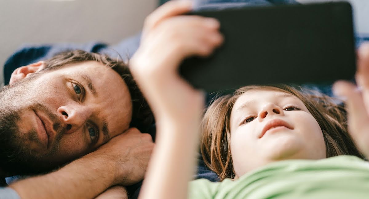 Pai e filho assistindo juntos a um vídeo no smartphone.