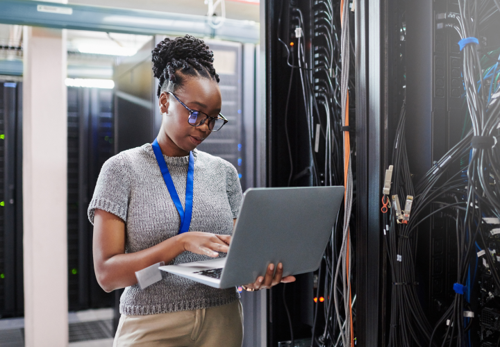 Una donna in una sala server che guarda il proprio computer.