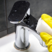 gloved hand cleaning bathroom faucet with white sponge