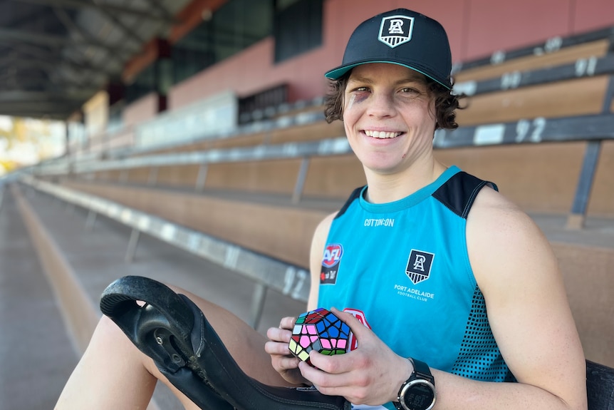 Close-up of Ebony O'Dea smiling with a Rubik's cube and her unicycle in the Port Adelaide grandstand