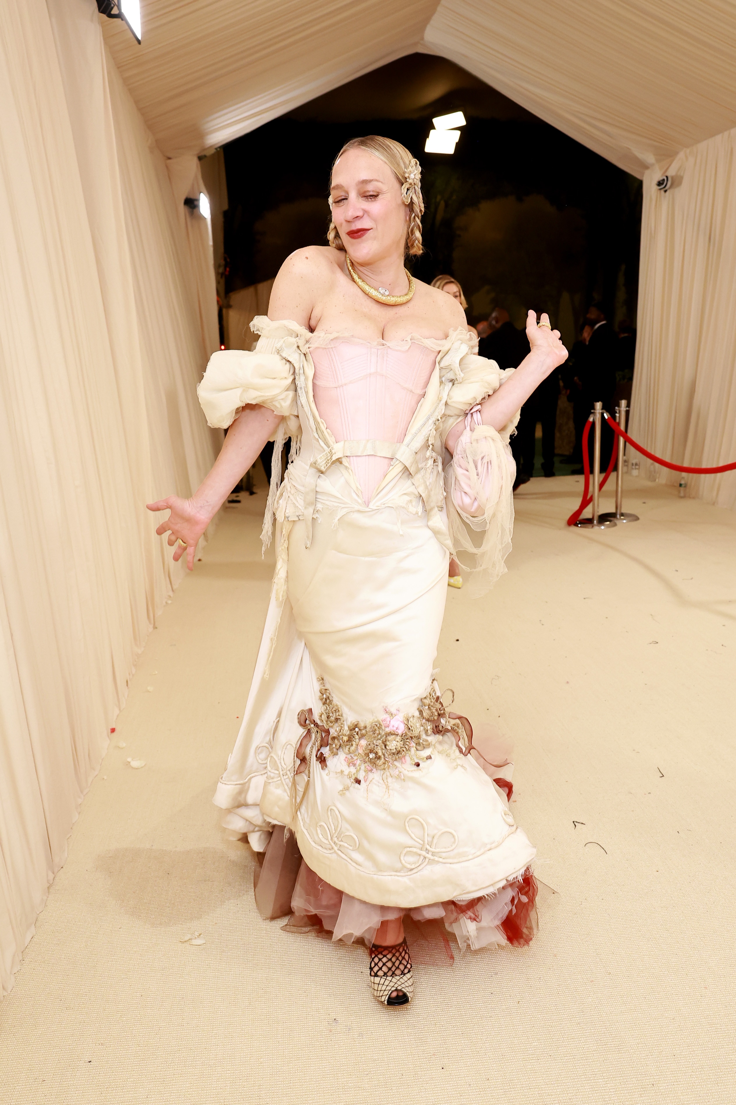Chloe Sevigny wearing a white and cream gown smiles and poses for the camera