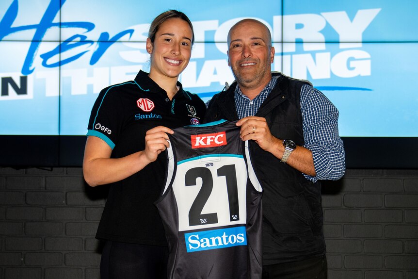 Amelie Borg is presented her Port Adelaide jumper, holding it next to her father