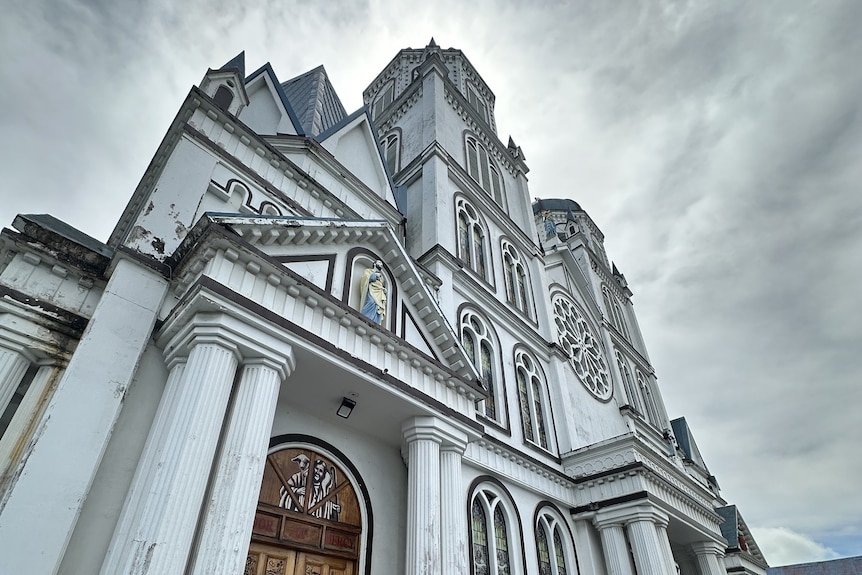 The white facade of Immaculate Conception Cathedral in Samoa, under a grey sky.