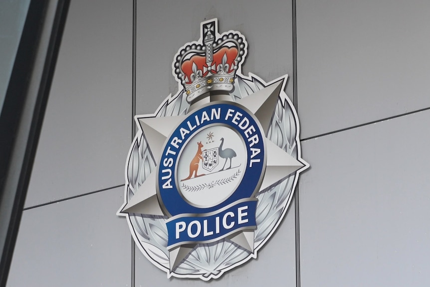 The Australian Federal Police logo mounted to a white paneled wall.