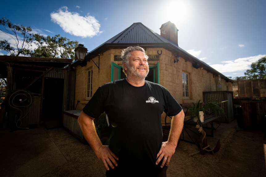 A pub owner stands outside the entrance to his hotel.