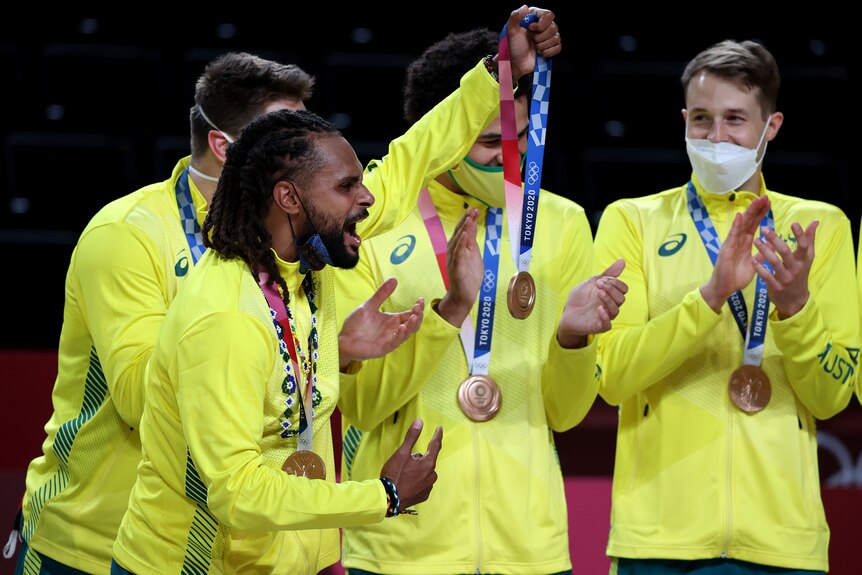 Australian men's basketball team members celebrate with their Olympic bronze medals, as most of them wear masks.