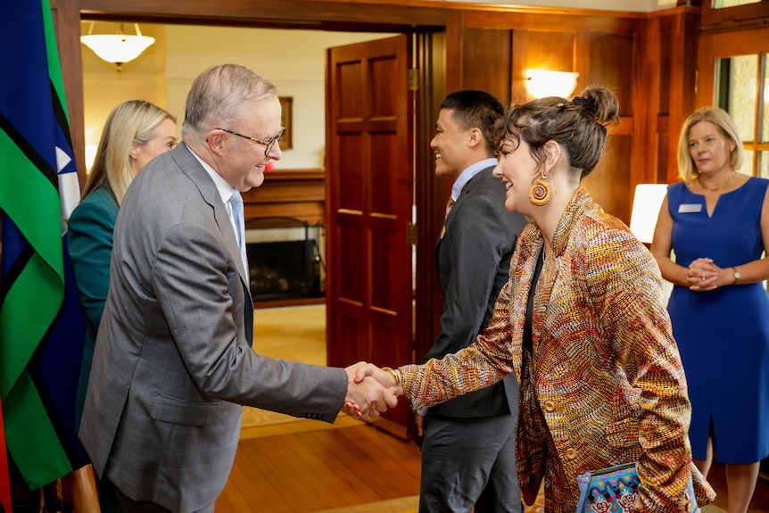 The prime minister shakes the hand of a young woman