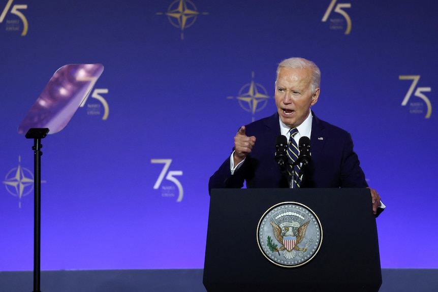 Joe Biden points his finger while he delivers a speech with teleprompters to his left
