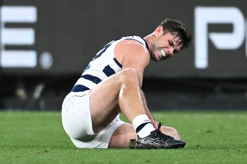 Tom Hawkins clutches his left foot in agony