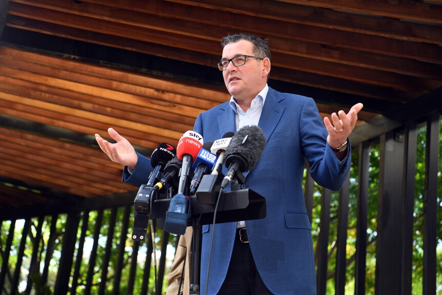 Victorian Premier Daniel Andrews speaks to media during a press conference with his hands outstretched.