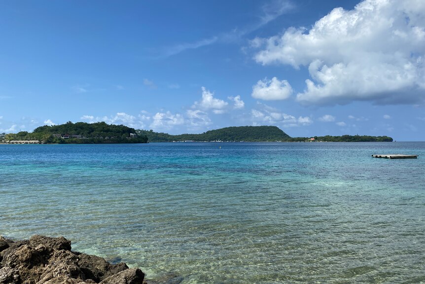 A view of a bay of tropical turquoise water on a mostly sunny day.