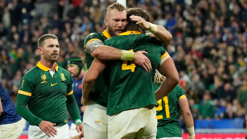 South African rugby players celebrate a try as French players stand dejected in the background.