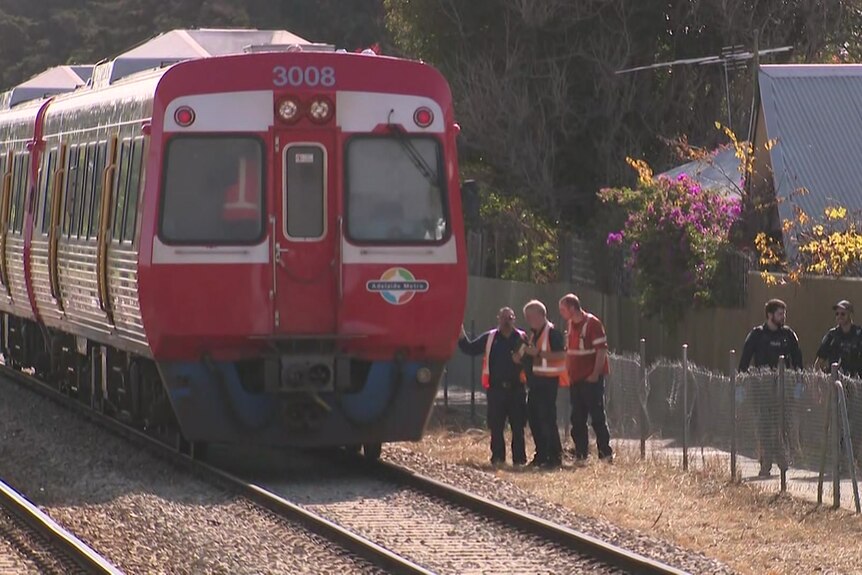 A train with police and three men in fluoro vests standing nearby