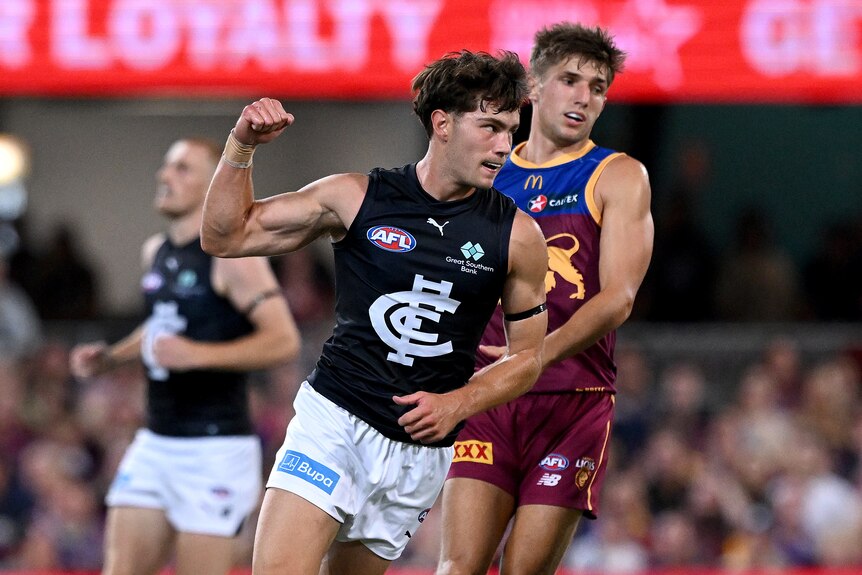 A Carlton AFL player pumps his fist in celebration after kicking a goal.