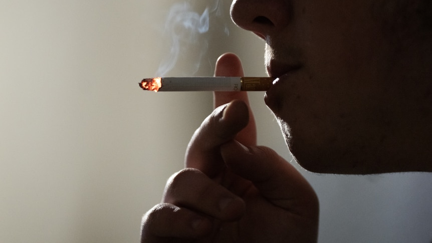 Silhouette of a man smoking a cigarette against white background. 