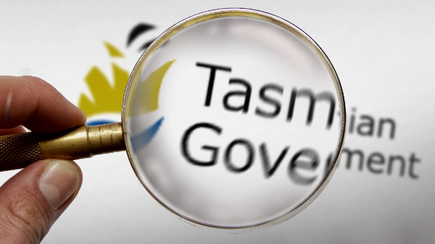 Hand holding a magnifying glass over Tasmanian Government letterhead.