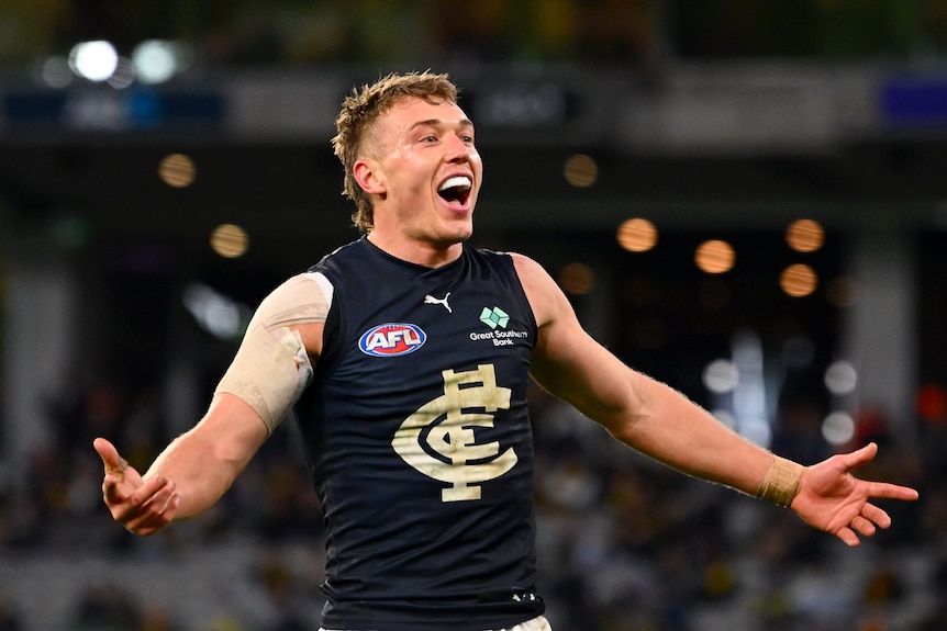 A smiling Carlton captain Patrick Cripps holds his arms out in celebration after a goal.