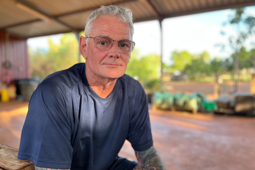 A man sits in a shed looking at the camera