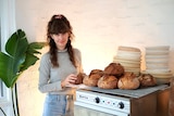 Mary Grace Quigley stands with loaves of sourdough bread in her kitchen.