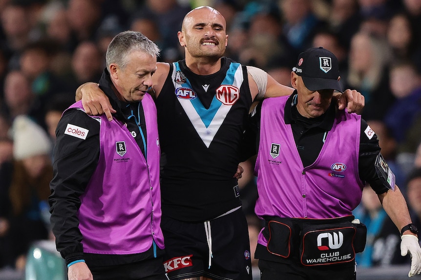 Sam Powell-Pepper grimaces as club doctors help him from the field