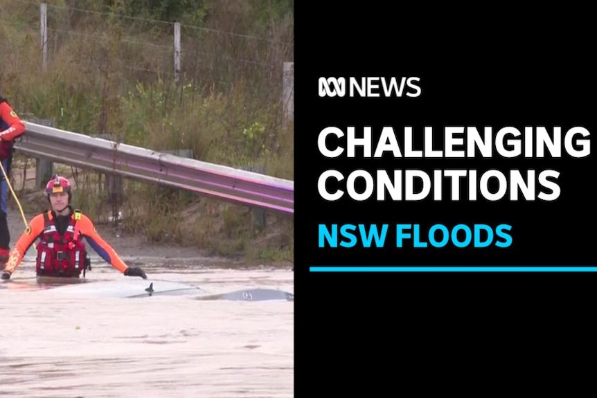 Challenging Conditions, NSW Floods: An emergency worker waist deep in floodwaters. A colleague behind him holds a rope.