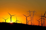 Wind turbines on a ridge with the rising sun in the background