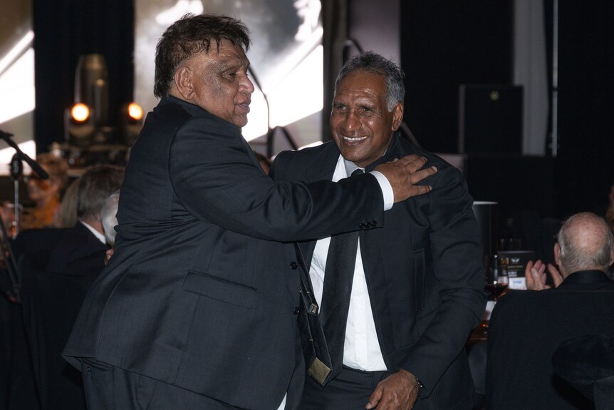 Two men hugging at a presentation night