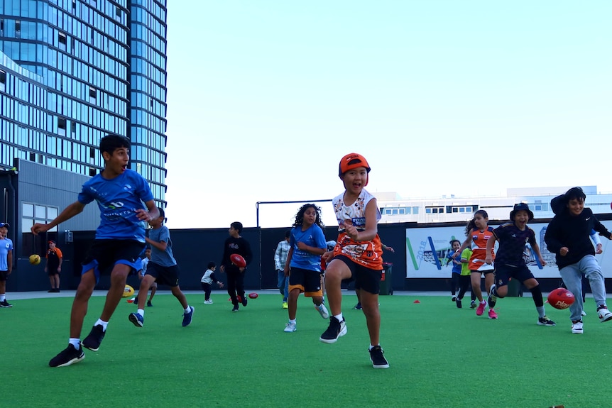 Excited kids running around with AFL balls.