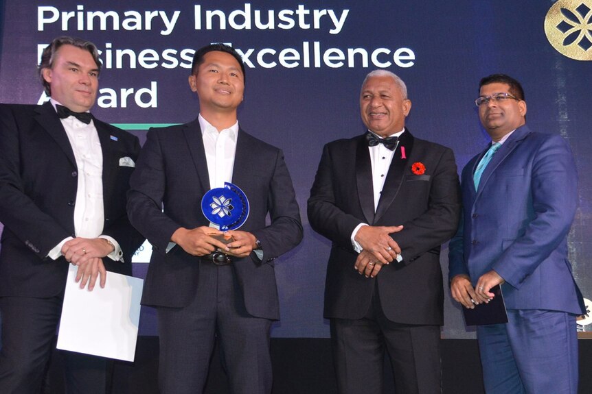 Four men in suits pose for onstage at the  Prime Minister’s International Business Awards. 