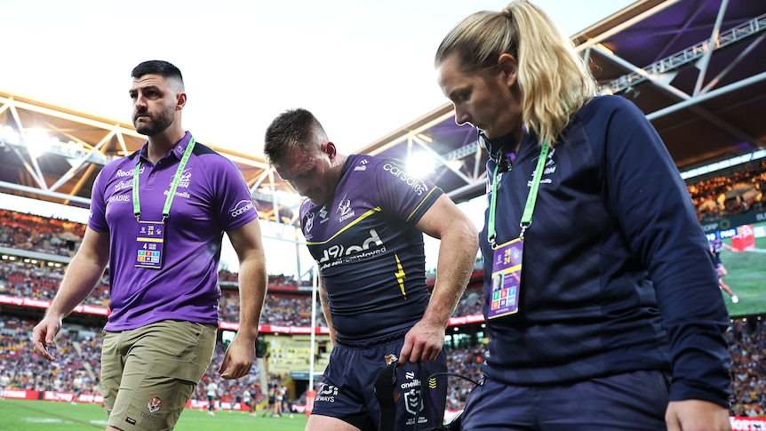 Cameron Munster walks with two of Melbourne Storm's medical staff after being injured during Magic Round.