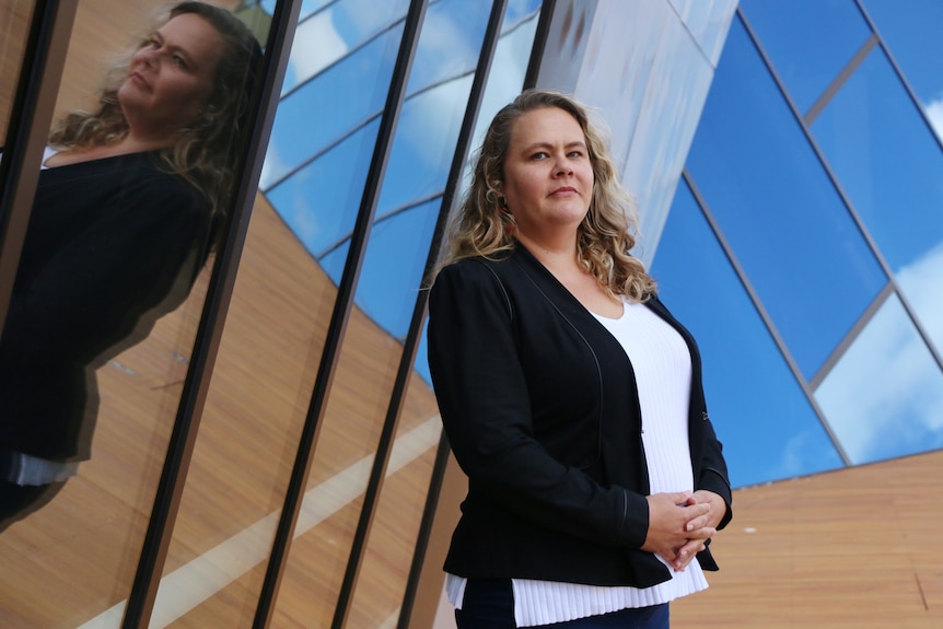 A woman standing next to reflective glass.