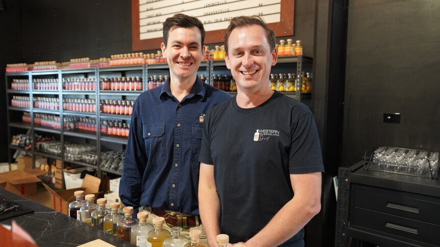 Two men stand behind a bar