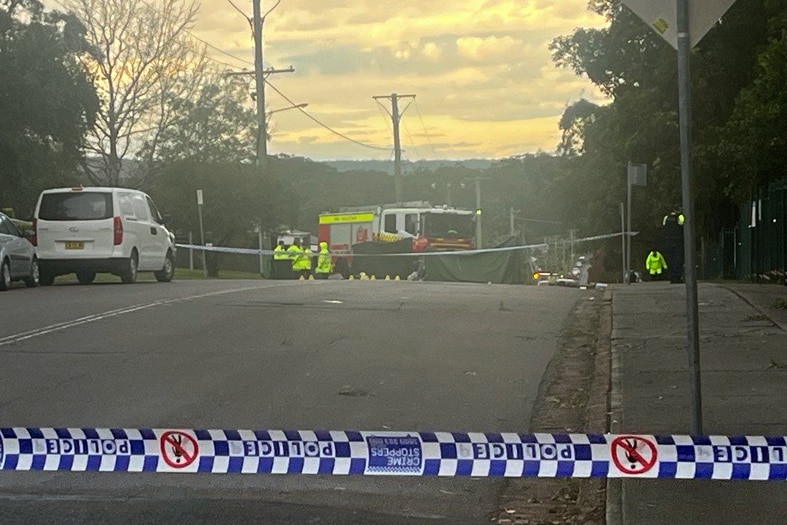 Fire and emergency services crowd around the site of an accidennt, covered in sheeting.