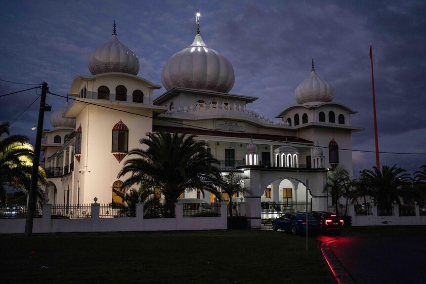 A Sikh gurdwara at night. A large building with round turrets.